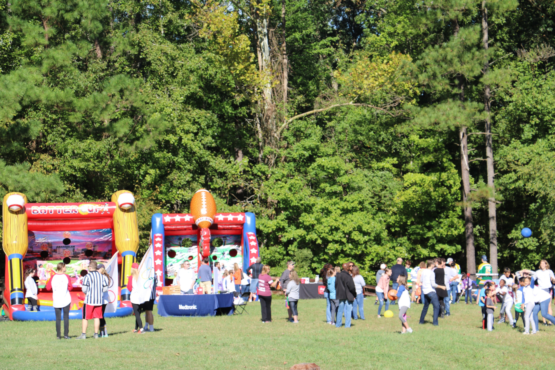 Camp Woodbine families gathered on the field with inflatable games and sponsor booths